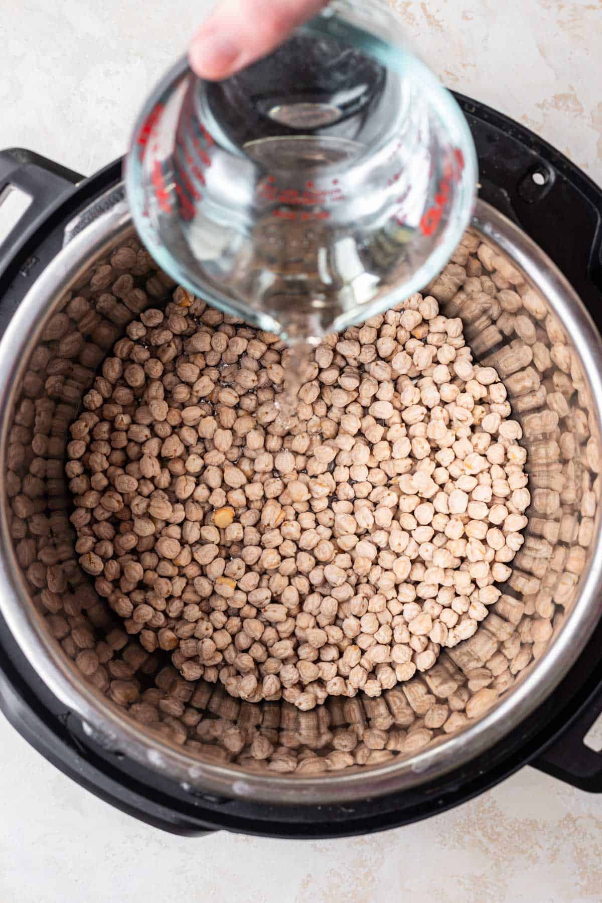 Pouring water over chickpeas in Instant Pot.