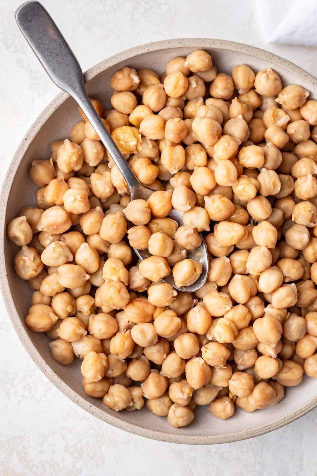 Bowl of cooked chickpeas with spoon.