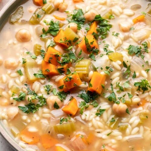 Lemon orzo soup in bowl garnished with fresh parsley.