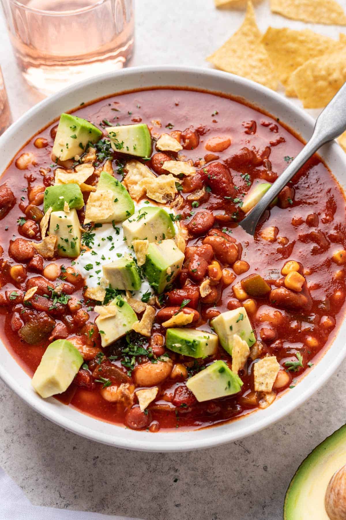 Bowl of vegan chili garnished with cubed avocado.