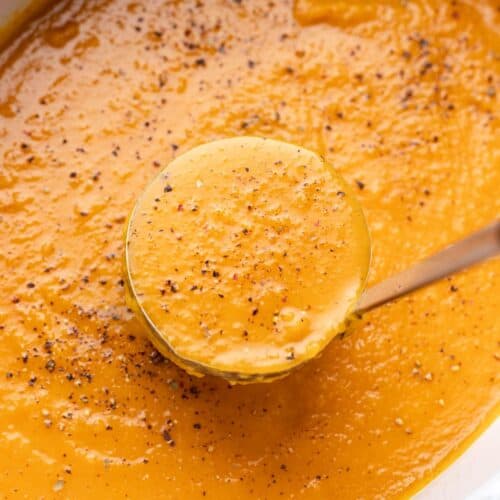 Ladle of creamy butternut squash soup in slow cooker.