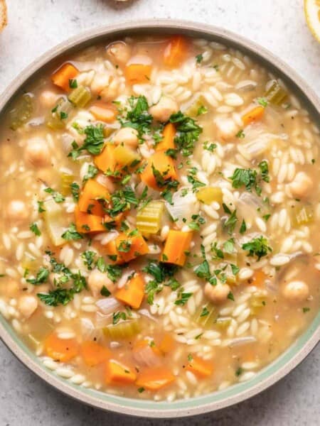 Orzo soup garnished with fresh parsley and lemon.