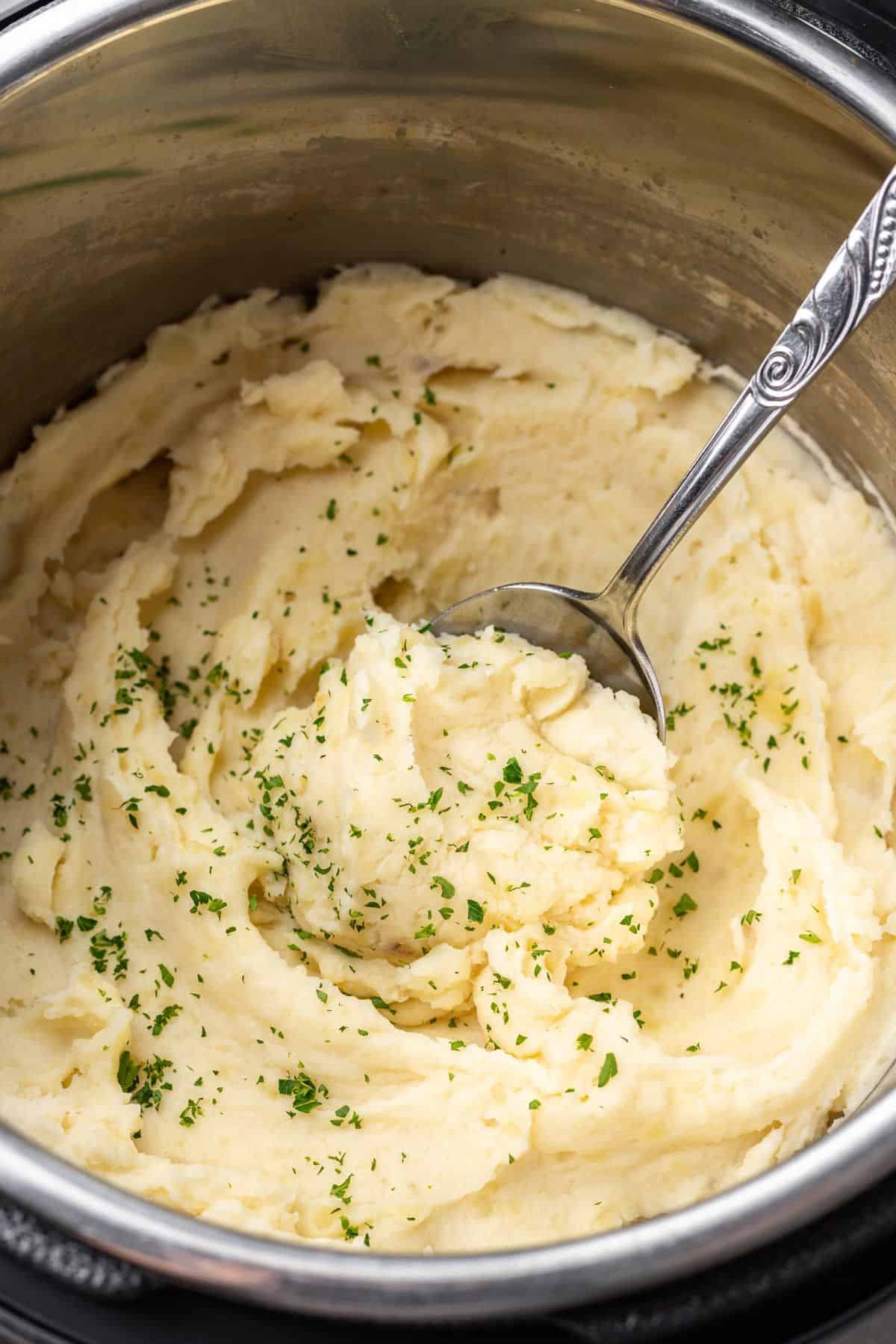 Mashed potatoes in the Instant Pot with a serving spoon.