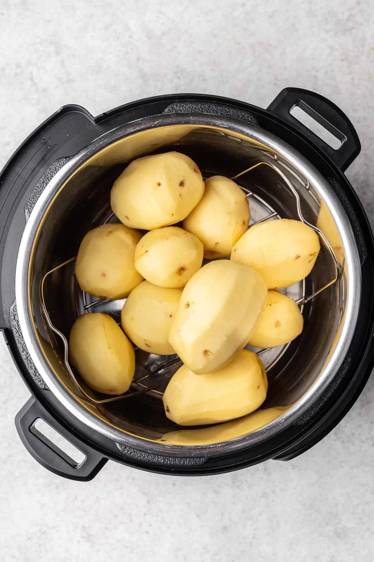 Peeled potatoes on a trivet with water in the Instant Pot.