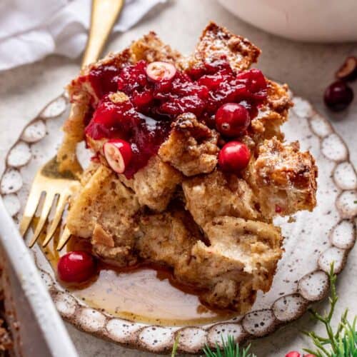Serving of french toast casserole topped with cranberry sauce and maple syrup.