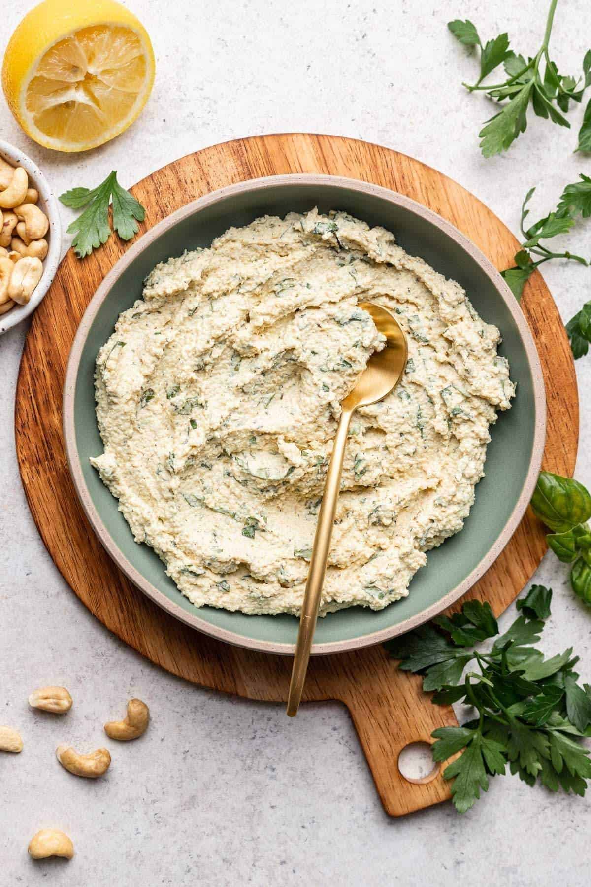 Cashew ricotta in blue serving bowl with gold spoon.