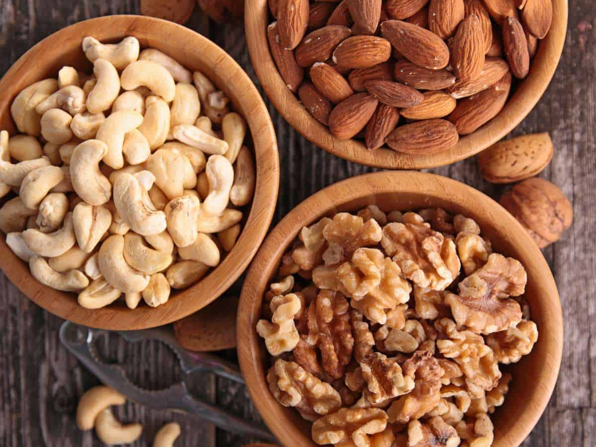Walnuts, almonds, and cashews in individual bowls.