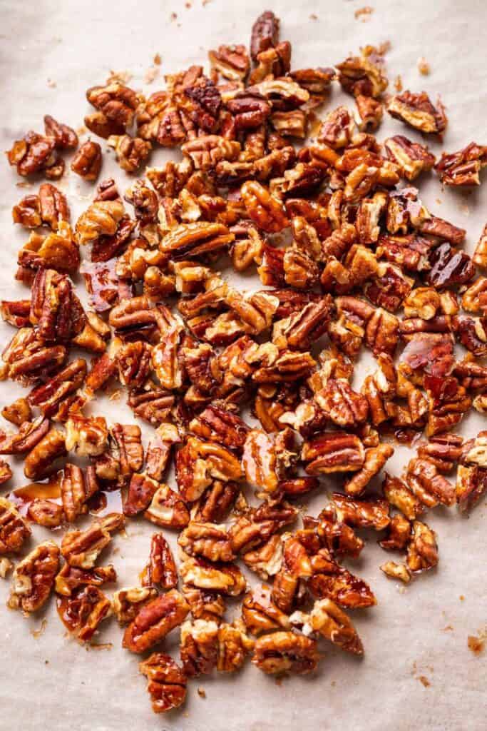 Glazed pecans on sheet pan lined with parchment paper.