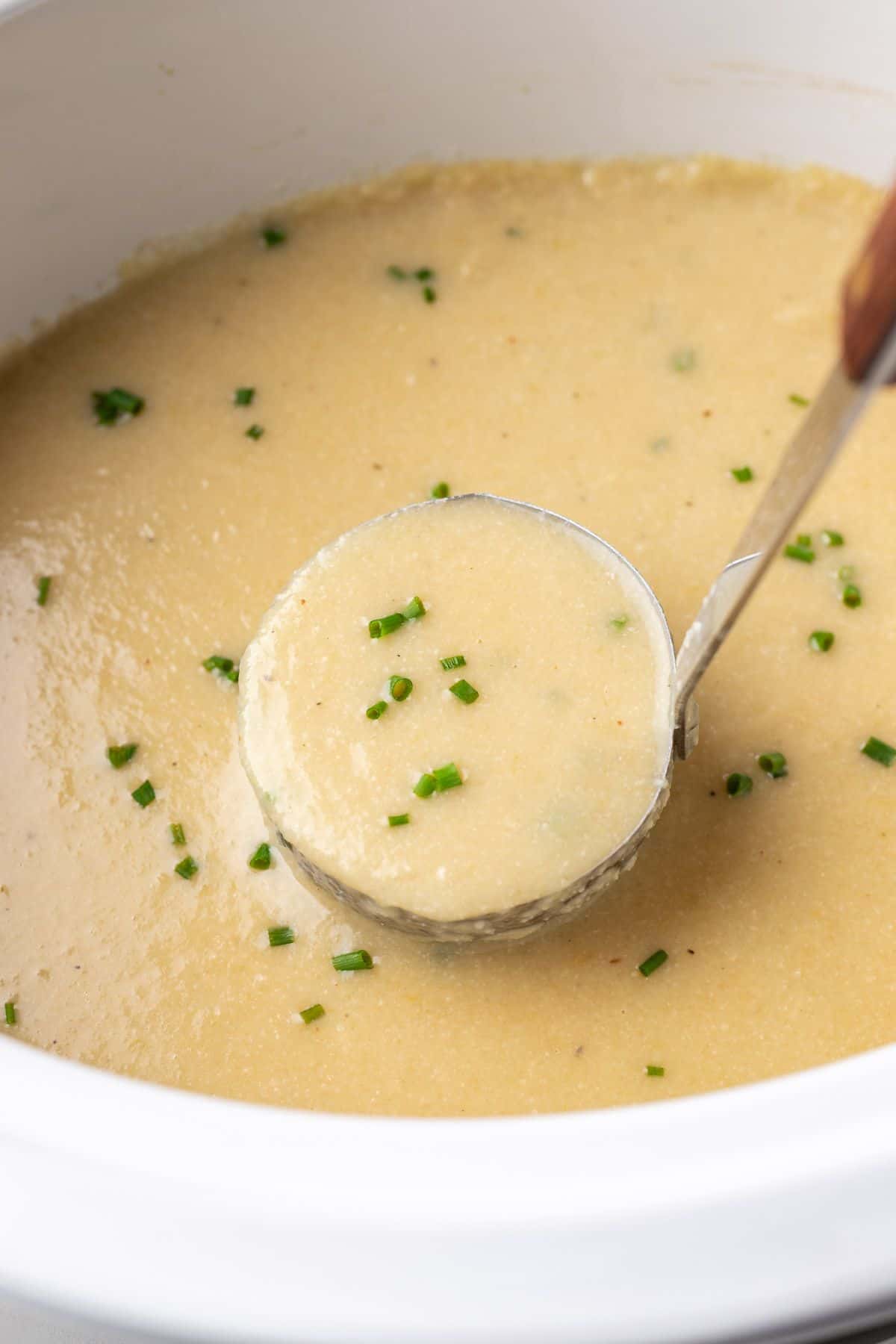 A ladle of cauliflower soup in crockpot. 
