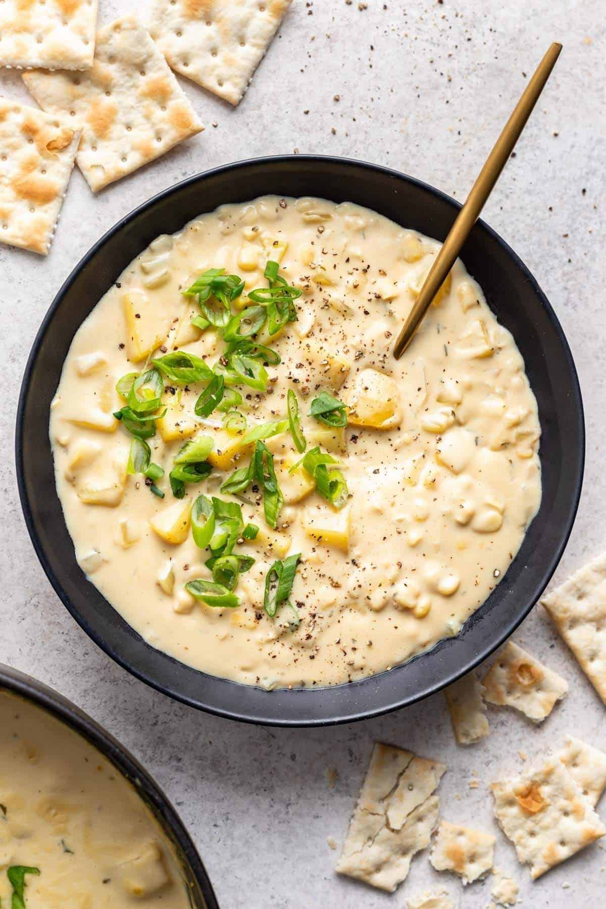 Final vegan corn chowder recipe served in black bowl with crackers.