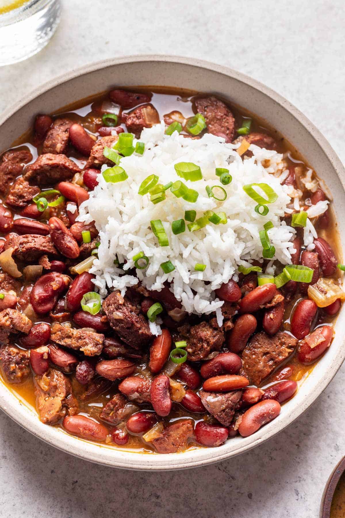 Vegetarian instant pot red beans and rice in white serving bowl with white rice and green onion.