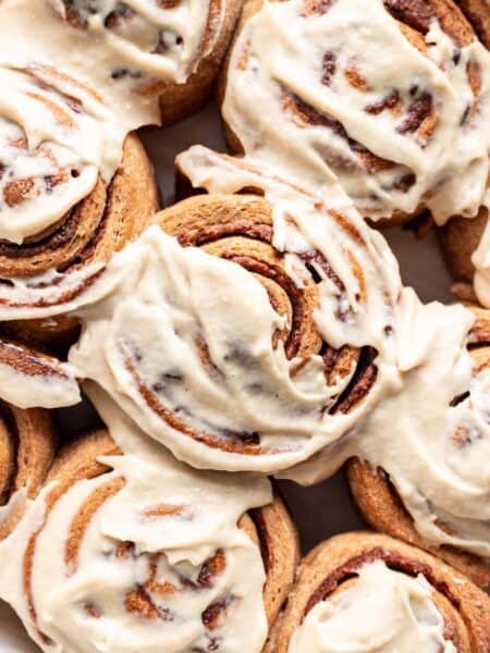 Closeup of baked whole wheat cinnamon rolls with homemade frosting slathered on top.