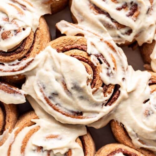 Closeup of baked whole wheat cinnamon rolls with homemade frosting slathered on top.