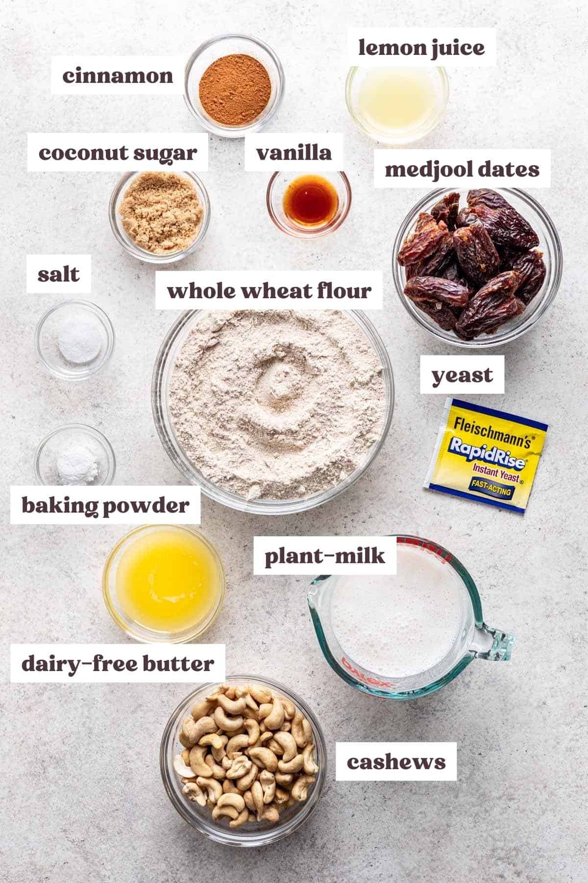 Overview of the ingredients you will need to make this whole wheat cinnamon rolls recipe and homemade frosting. Ingredients are measured and labeled in small glass bowls.