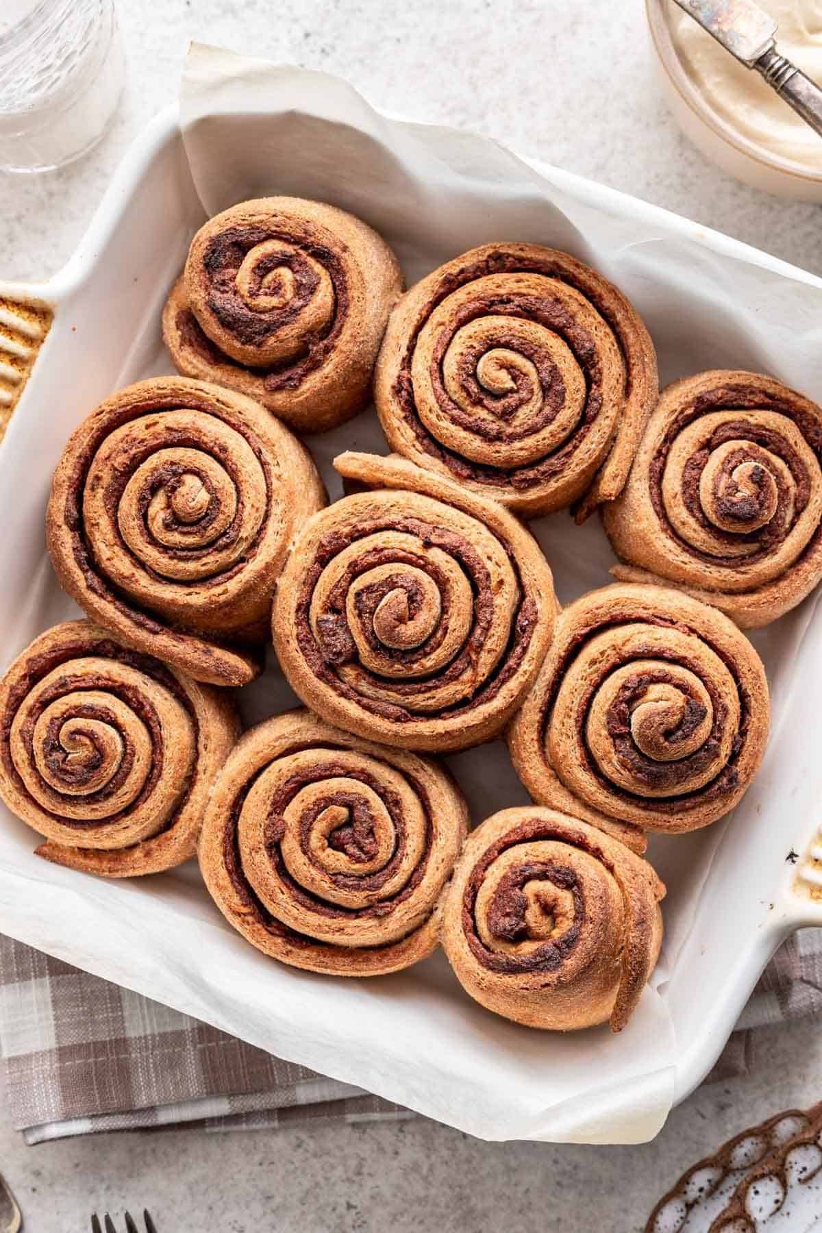 Baked whole wheat cinnamon rolls in a white, square baking dish.