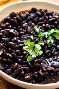 A bowl of Copycat Chipotle Black Beans garnished with fresh cilantro, showcasing their rich, dark color and hearty texture, ready to serve.