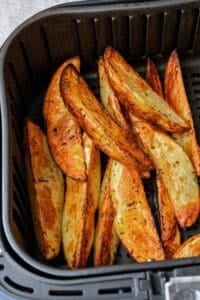 Russet potato wedges after air frying in air fryer basket.